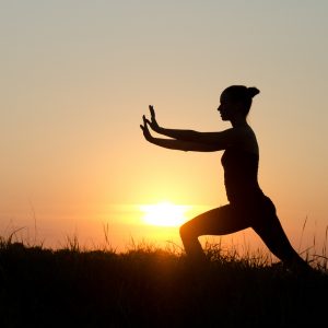 Woman praticing tai chi chuan at sunset.